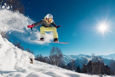 Girl is jumping with snowboard from the hill