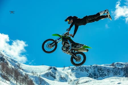 racer on a motorcycle in flight, jumps and takes off on a springboard against the snowy mountains