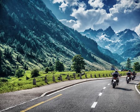 Motorcyclists on mountainous road, enjoying tour along Alps, summertime activities, wonderful mountain landscape, extreme vacation concept